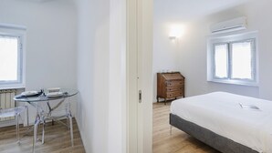 A room with a bed, a dresser, a table with chairs, and a window. - Cute Nest Near the Center by Wonderful Italy (Genoa)