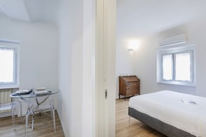 Una habitación con una cama, un tocador, una mesa con sillas y una ventana.