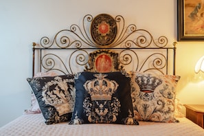 Un letto con testiera in metallo decorata, cuscini ornamentali e un quadro appeso sopra.