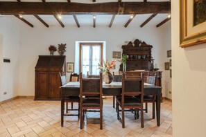 Zona pranzo con tavolo e sedie in legno, un armadietto e una finestra con tende.