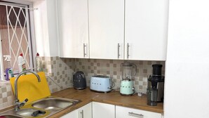 Una cucina con mobili bianchi, un lavello doppio, un tostapane, un frullatore e una macchina per il caffè.