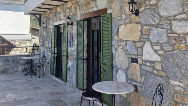 A stone building with a covered patio, outdoor seating, and a view of mountains. - Bahab Plus Guest House (Söke)