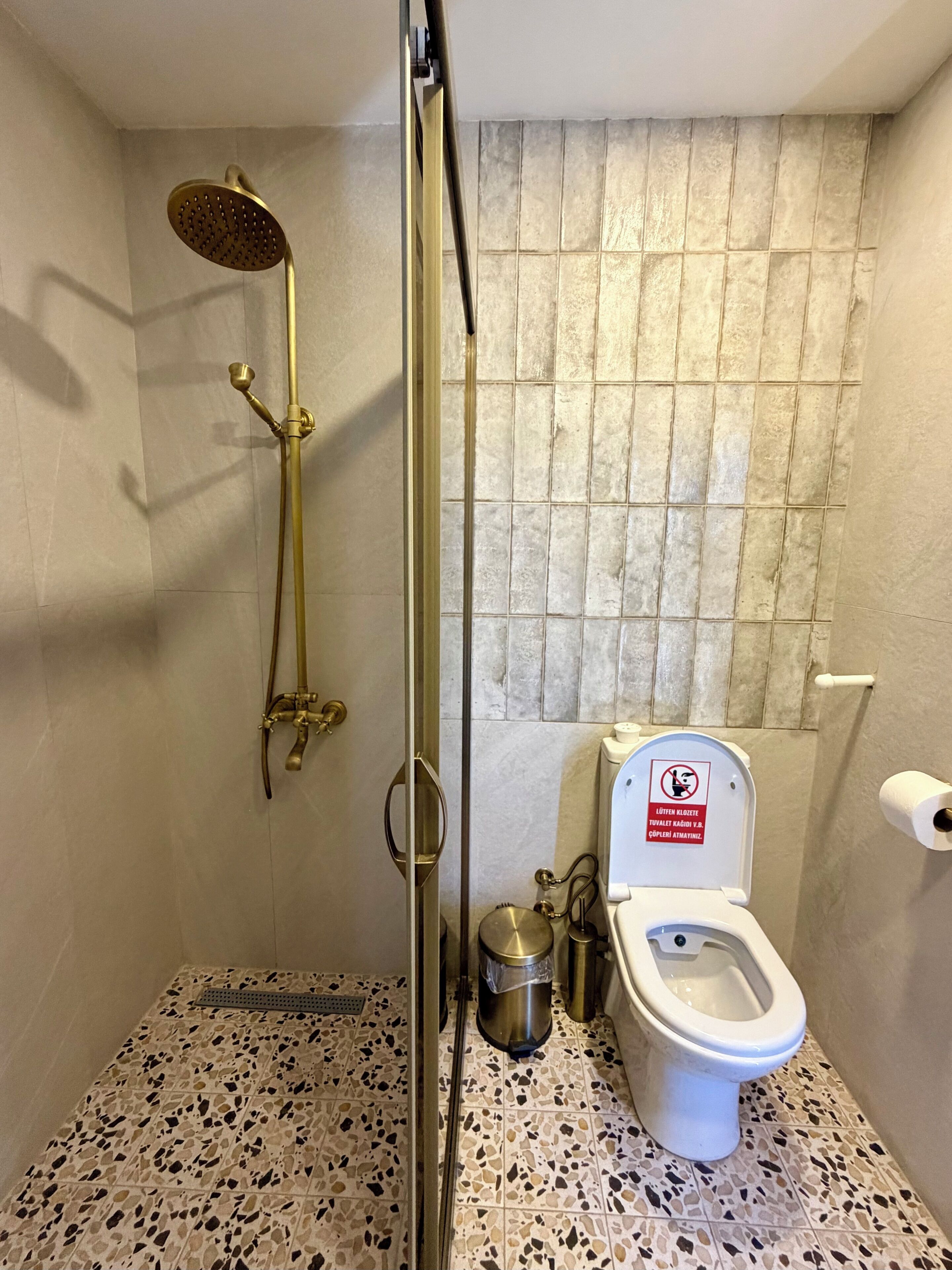 Un baño con ducha, inodoro y piso de baldosas.
