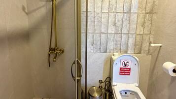 Un baño con ducha, inodoro y piso de baldosas.