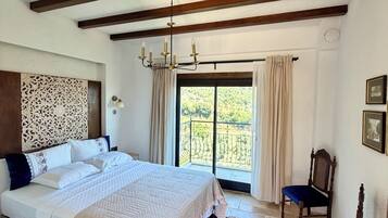 Um quarto com uma cama grande, um candelabro, vista pela janela e parede estampada.