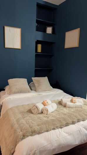 Ein Hotelzimmer mit Bett, Kissen, einer flauschigen Decke und einer Willkommensbox.