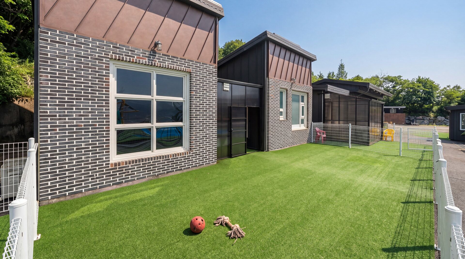 A modern building with a brick facade, large windows, and a well-maintained lawn.