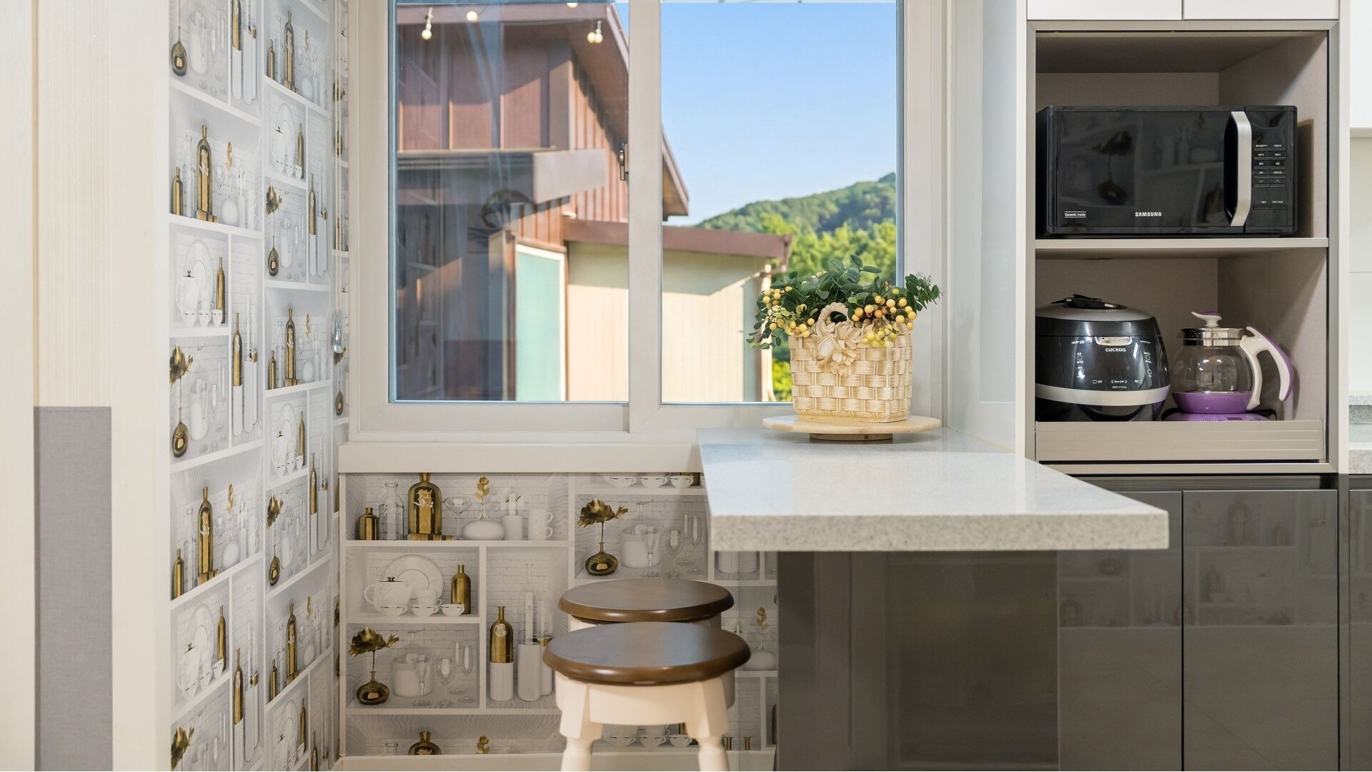 A kitchen with a built-in shelf, a window with a view, and a countertop with a microwave and a coffee maker.
