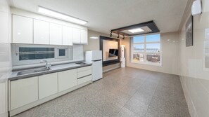 A modern kitchen with white cabinets, a built-in microwave, a refrigerator, and a large window offering a view.