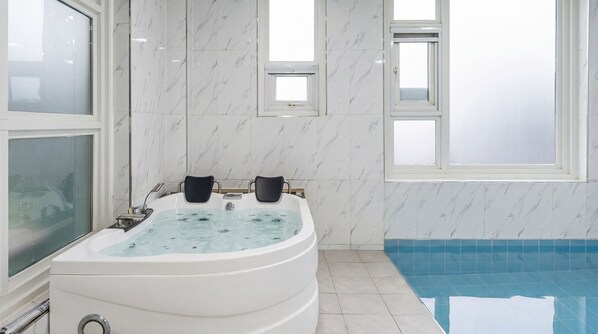 A bathroom with a jacuzzi, a small window, and a pool.