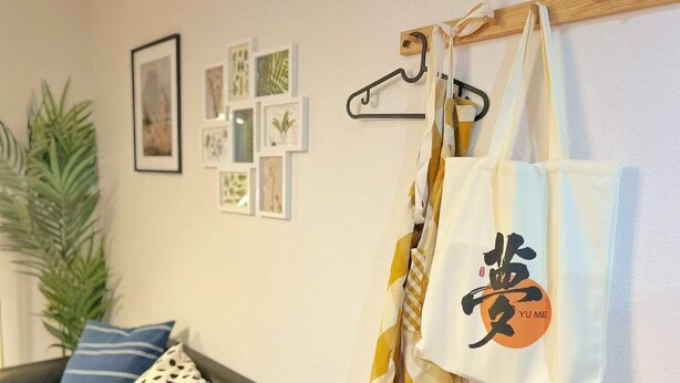 Ein Zimmer mit einer schwarzen Couch, einem Kissen mit Punkten und einem Kissen mit Streifen, sowie einer Wand mit gerahmten Bildern.