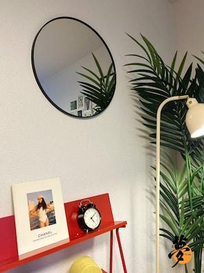 A wall with a round mirror, a red shelf with a framed picture and a clock, a lamp, and a potted plant. - YUME Yume Matsuyacho 301 ｜Namba/Shinsaibashi｜Walking distance from Matsuyacho station｜Family welcome (大阪市)