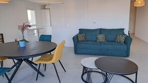 Una sala de estar moderna con un sofá, una mesa de comedor, sillas y una pequeña mesa de centro.
