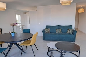 Una sala de estar moderna con un sofá, una mesa de comedor, sillas y una pequeña mesa de centro.