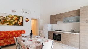 A modern kitchen with a built-in oven, a dining area with a table set for two, and a colorful sofa. - 'Corso Roma Home Gallipoli' Apartment with Air Conditioning (Gallipoli)