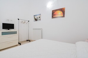 Une chambre à coucher avec un lit, une commode, un radiateur et des œuvres d’art murales.