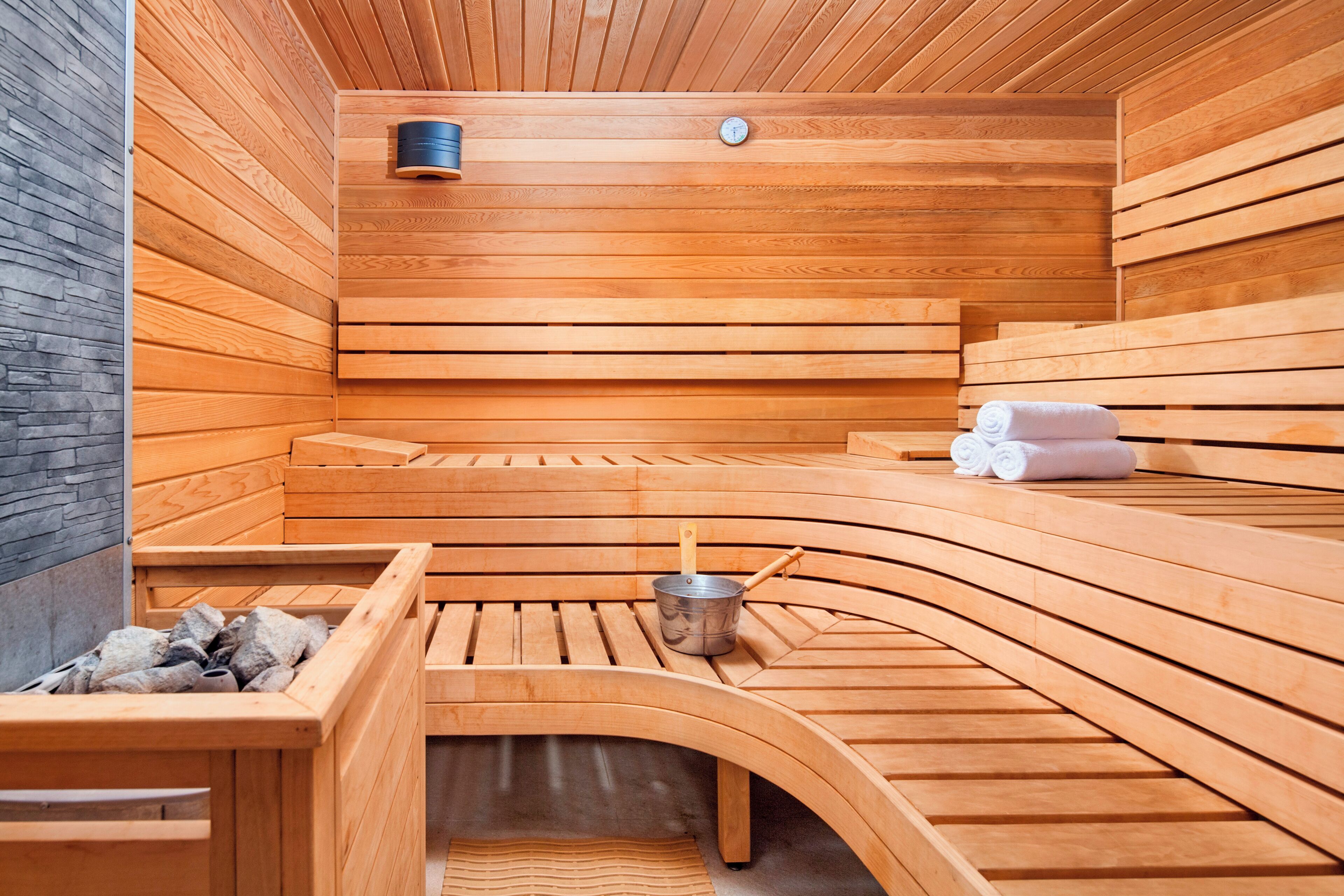 A sauna with wooden benches and a stone wall.