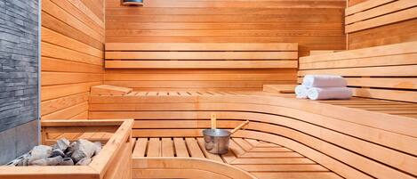 A sauna with wooden benches and a stone wall.