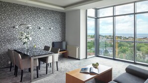 A modern living room with a large window, a dining area, and a TV. - Sea Premium Aparthotel (Gdynia)