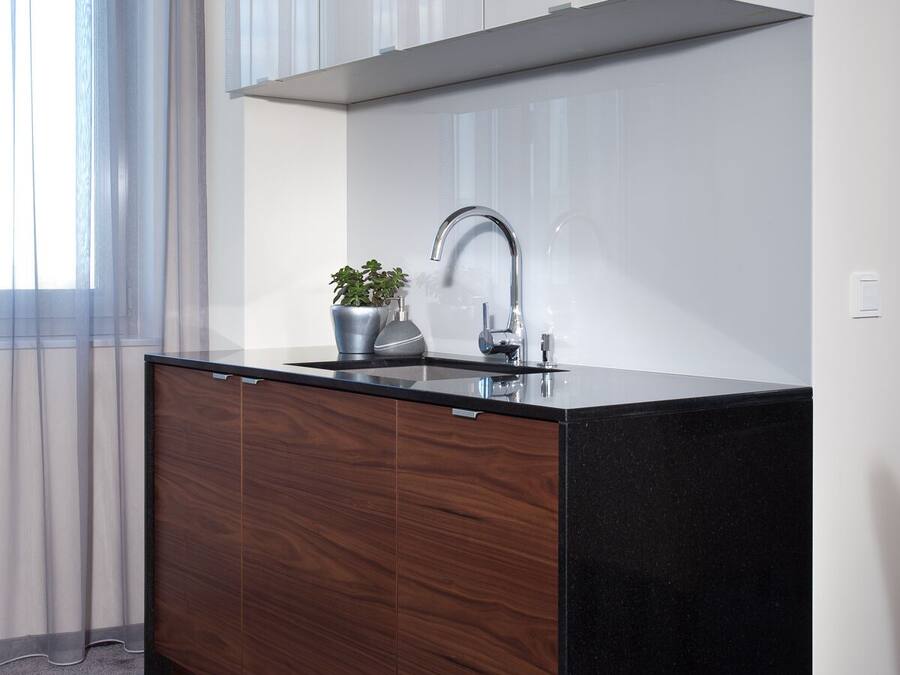 A modern kitchen with a black countertop, stainless steel faucet, and a built-in oven.