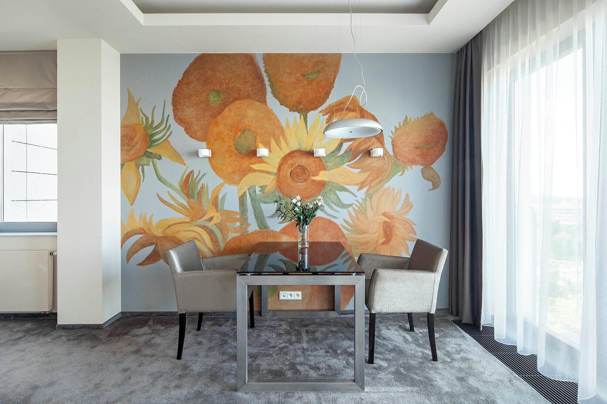 Una habitación moderna con una mesa de comedor, sillas, un florero con flores y un gran mural floral en la pared.