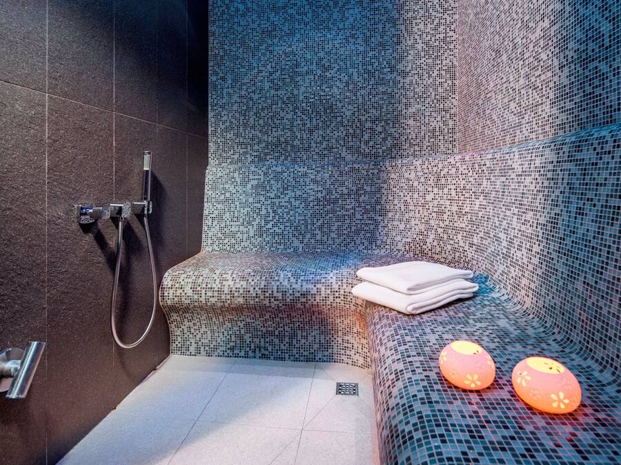 A modern bathroom with a shower, a towel rack, and a bench with decorative lights.