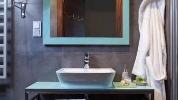 A modern bathroom with a large mirror, a sink, and a towel rack.
