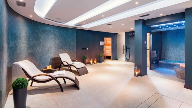 A modern spa area with lounge chairs, a heated floor, and a visible sauna entrance. - Sea Premium Aparthotel (Gdynia)