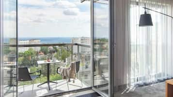 A balcony with a table and chairs, a view of the city, and a large window.