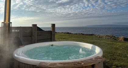 At the edge of the sea, this stunning house has a wood fired hot tub.