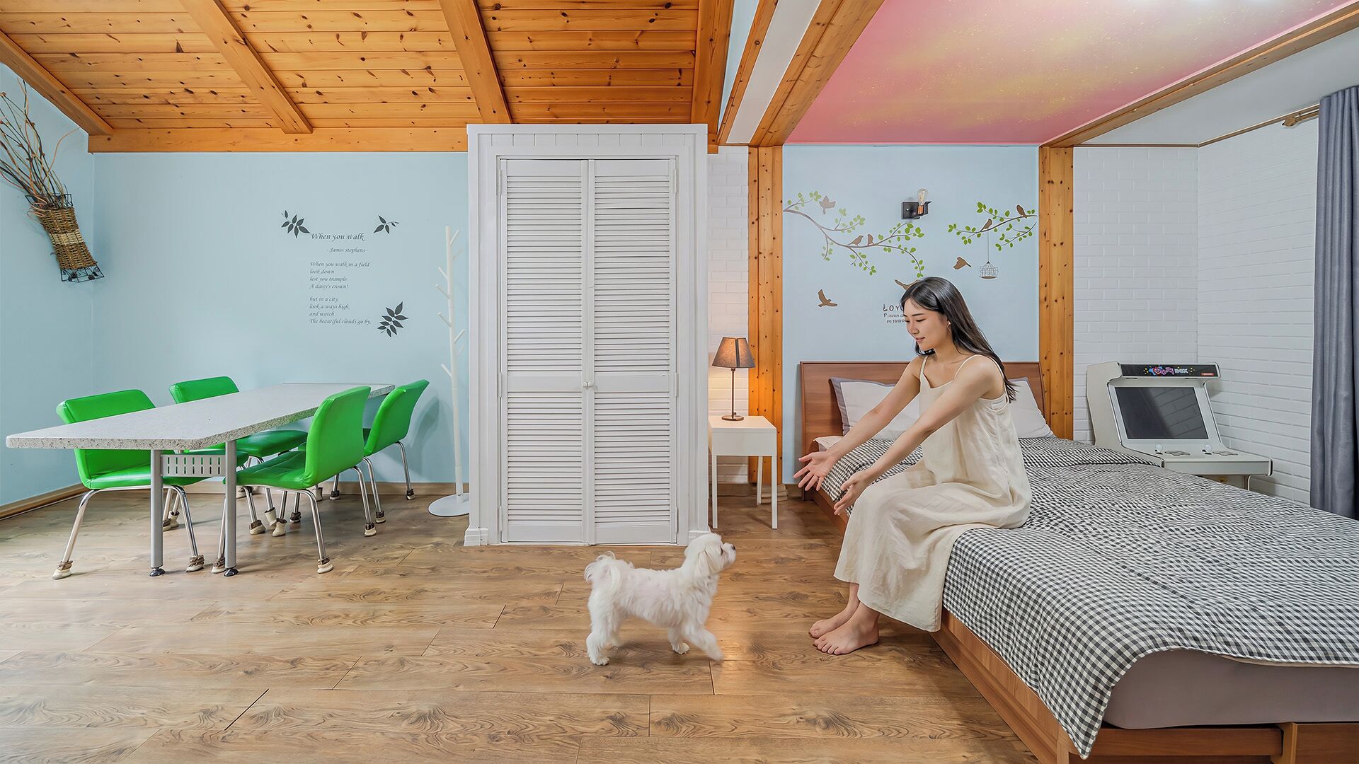 Una habitación con una cama, un escritorio, una silla, una mesita pequeña y un perro.