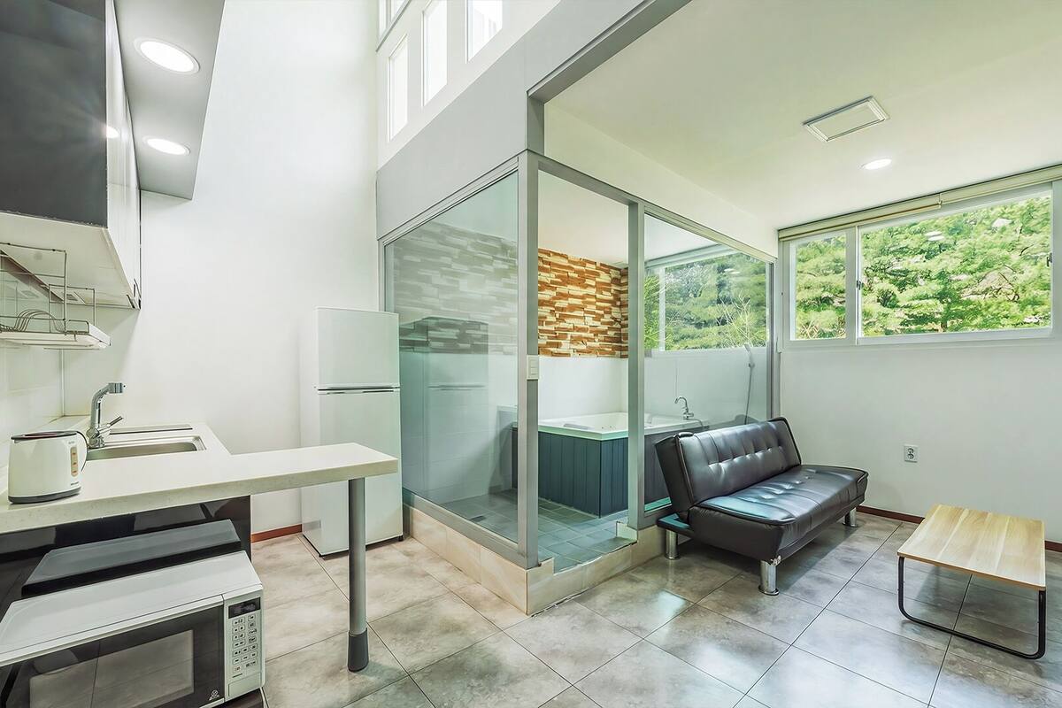 A modern bathroom with a glass shower enclosure, a bathtub, and a seating area.