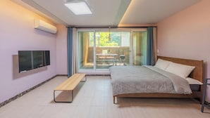 Ein Schlafzimmer mit einem Bett, einer Bank, einem Fernseher und einer Glastür, die zu einem Außenbereich führt.