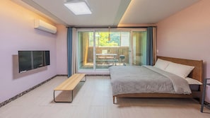 Une chambre à coucher comprenant un lit, un banc, une télévision et une porte-fenêtre coulissante donnant sur un espace extérieur.
