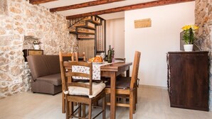 A rustic dining area with a stone wall, wooden furniture, and a staircase. - Vacation home Antonio in the old town of Vrbnik, beautifully furnished (Vrbnik)