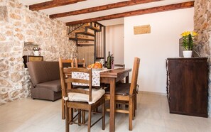 A rustic dining area with a stone wall, wooden furniture, and a staircase. - Vacation home Antonio in the old town of Vrbnik, beautifully furnished (Vrbnik)