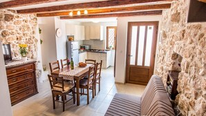 A dining area with a table and chairs, a sofa, and a kitchen in the background. - Vacation home Antonio in the old town of Vrbnik, beautifully furnished (Vrbnik)