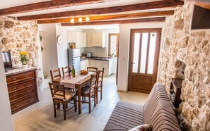 A dining area with a table and chairs, a sofa, and a kitchen in the background. - Vacation home Antonio in the old town of Vrbnik, beautifully furnished (Vrbnik)