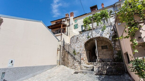 A narrow street with a stone archway, a staircase, and buildings with balconies and windows. - Vacation home Antonio in the old town of Vrbnik, beautifully furnished (Vrbnik)
