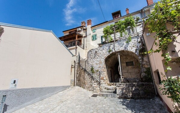 A narrow street with a stone archway, a staircase, and buildings with balconies and windows. - Vacation home Antonio in the old town of Vrbnik, beautifully furnished (Vrbnik)