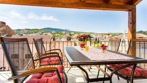 A covered outdoor seating area with a table and chairs, a view of the cityscape, and a mountain in the distance. - Vacation home Antonio in the old town of Vrbnik, beautifully furnished (Vrbnik)
