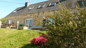 A stone building with a sloped roof, a door, and a small garden with pink flowers. - Family home on the Breton Crozon Peninsula, dogs welcome, view on the sea (Lanvéoc)