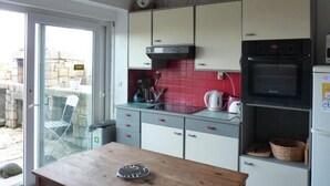 A kitchen with a wooden table, cabinets, a stove, and a refrigerator. - Family home on the Breton Crozon Peninsula, dogs welcome, view on the sea (Lanvéoc)