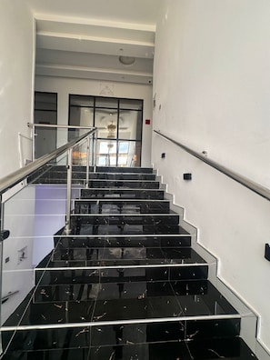 A staircase with black marble steps and metal railings, leading to an interior space with a chandelier. - Shalom Hotel (Mkushi)