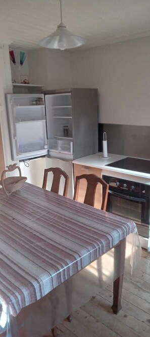 Eine Küche mit Esstisch, Stühlen, einem Kühlschrank, einem Herd und einer Pendelleuchte.