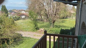 Een balkon met uitzicht op een gazon, bomen en huizen op de achtergrond.
