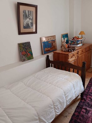 Ein Schlafzimmer mit einem Einzelbett, einem Schminktisch und Bildern an der Wand.