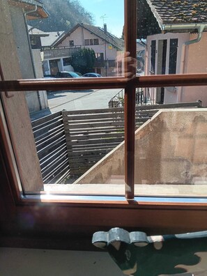 Blick aus einem Fenster auf eine Wohngegend mit Straße, parkenden Autos und Häusern.