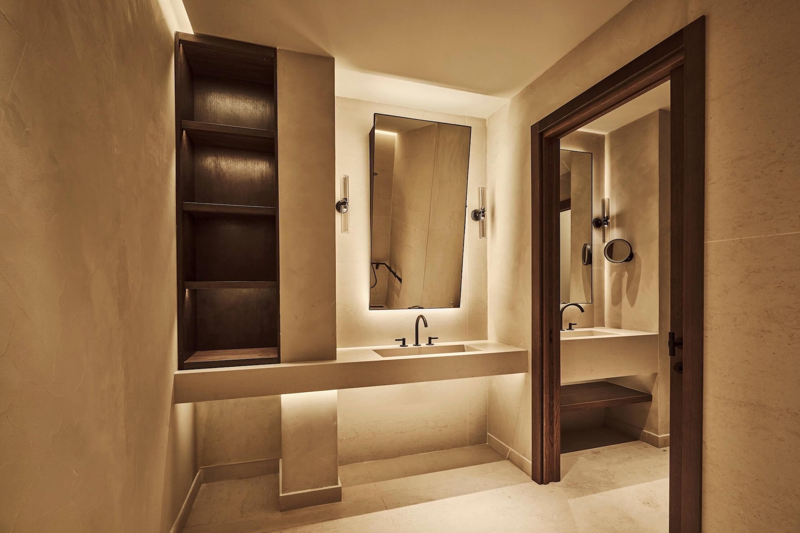A modern bathroom with a large mirror, a built-in shelf, and a vanity with a sink.