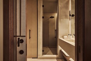 Une salle de bain moderne avec une douche à l’italienne, un meuble-lavabo avec un miroir et un porte-serviettes.